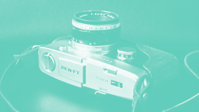 Vintage Olympus Pen-FT film camera with Zuiko lens, shown in artistic teal overlay. Perfect for photography blogs, camera reviews, and sites focused on classic film cameras and analog techniques.