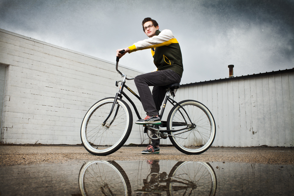 teen boy on a bike with water reflection in forground